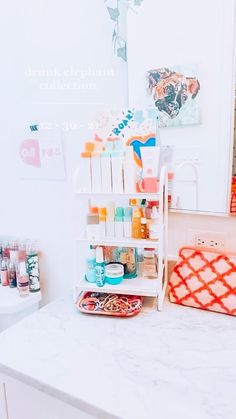 a white counter top sitting next to a bathroom sink under a mirror with lots of items on it