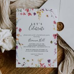 a wedding card with flowers on it and a wax stamp next to some other items