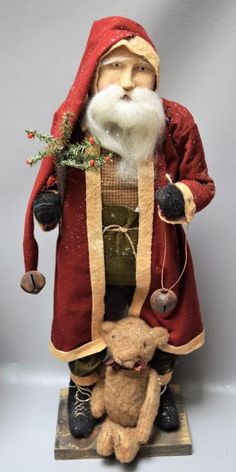 a santa clause holding a teddy bear on top of a wooden stand with bells and decorations