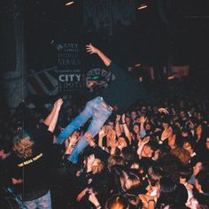 a crowd of people at a concert with their arms in the air and one person jumping up into the air