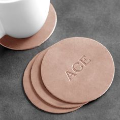 four coasters with the word aoe on them next to a cup of coffee