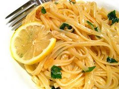 a plate of pasta with lemon and parsley on the side next to a fork