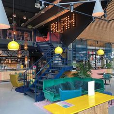 the inside of a restaurant with colorful furniture and lights hanging from the ceiling above it