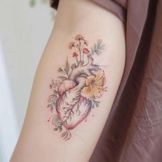 a heart tattoo with flowers and leaves on the right side of the arm is shown