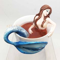 a cup filled with liquid and a mermaid figurine sitting in the bottom one