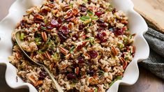 a white bowl filled with rice and cranberries on top of a wooden table