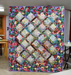 a quilt is hanging on the wall in a room with tables and chairs around it