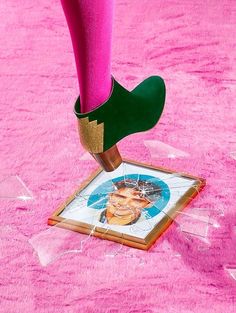 a person's feet with pink socks and green shoes on top of a painting