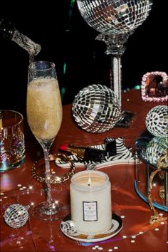 a table topped with two wine glasses and a candle next to a mirror disco ball