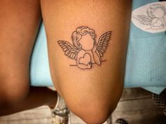 a tattoo on the leg of a woman with an angel sitting on top of it