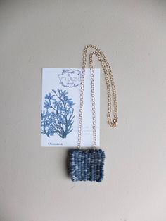 a blue and white necklace sitting on top of a piece of paper next to a card