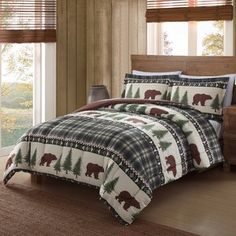 a bed in a bedroom with bear and pine trees on the comforter, next to a window