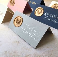 four different colored business cards sitting on top of each other with gold and silver buttons