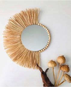 a round mirror sitting on top of a table next to dried plants and mushrooms in front of it