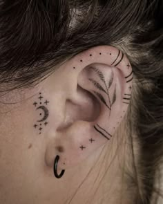 a woman's ear with an arrow and stars tattoo on her left behind the ear