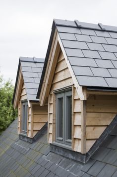 two small wooden buildings with windows and shingles on the roof, one has a black slate