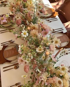 the table is set with flowers and place settings for guests to sit down at it