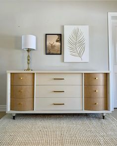 a white and wood dresser sitting in a living room next to a painting on the wall