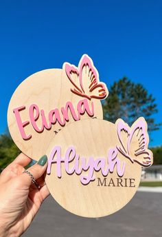 a person holding up two wooden signs that say, elana and aluna marie