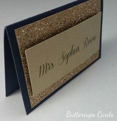 a close up of a place card holder on a white surface with gold glitters