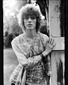 an old black and white photo of a woman leaning against a wall with her hands on the cross