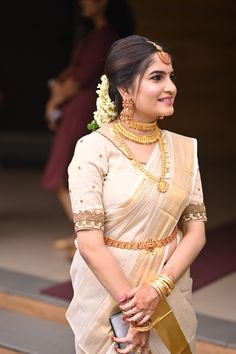 a woman wearing a white sari and gold jewelry