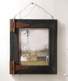 a painting hanging on the side of a wall next to a wooden frame with a windmill in it