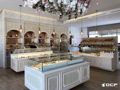 the interior of a pastry shop with lots of counter space and flowers hanging from the ceiling