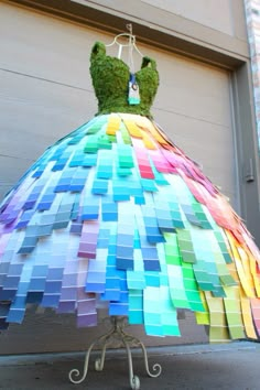 a dress made out of colored paper sitting on top of a metal stand