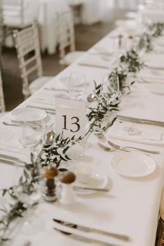 the table is set with white linens and silverware for an elegant wedding reception