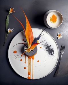 a white plate topped with an orange flower and sauce