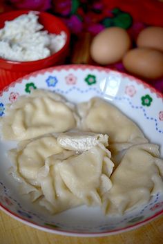 two bowls filled with dumplings on top of a wooden table next to eggs and other food