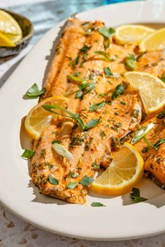 a white plate topped with fish and lemon slices