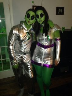 two people dressed in silver and green are standing next to each other wearing alien costumes