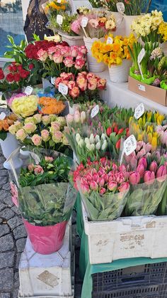 many different types of flowers are on display at the market stall, including tulips and roses