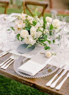 the table is set with white flowers and silverware