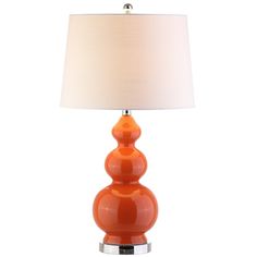 an orange table lamp with a white shade on the base and a silver metal base