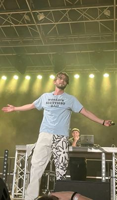 a man standing on top of a stage with his arms out in front of him