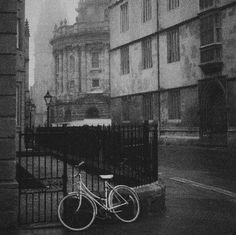 a bike parked on the side of a road next to a fence and building with windows