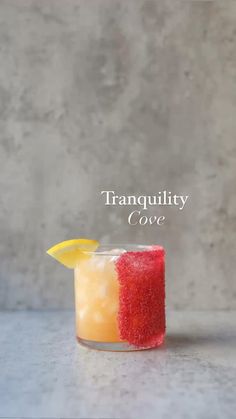 a small glass filled with liquid and a lemon wedge on the rim that says tranquility cove