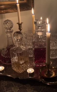 candles are lit on a tray with glassware and other items in front of a mirror