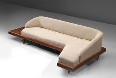 a beige couch sitting on top of a white floor next to a wooden frame with wheels