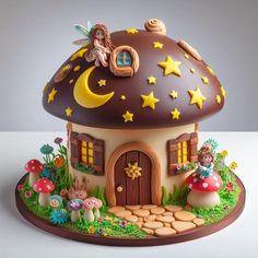 there is a cake that looks like a mushroom house with a fairy sitting on it