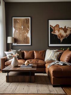 a living room filled with brown furniture and pictures on the wall above it's coffee table