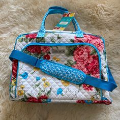 a white floral purse with blue handles sitting on top of a furnishing floor