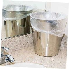 two trash cans sitting on top of a bathroom counter next to a sink and mirror