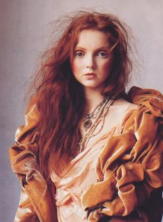 a woman with long red hair wearing a brown dress