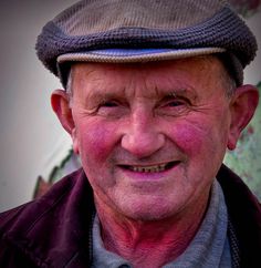 an older man wearing a hat smiling for the camera