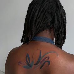 a man with dreadlocks has a tattoo on his back