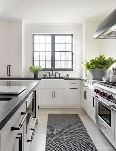 a kitchen with white cabinets and black counter tops, along with stainless steel oven hoods